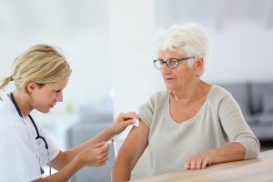 Nurse making vaccine injection to elderly patient